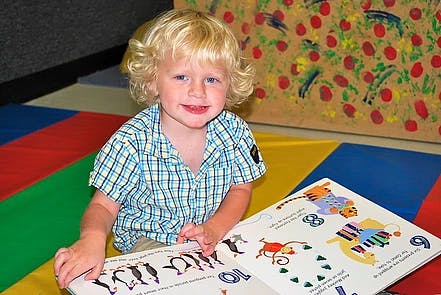 Child with blonde hair looking at an open book