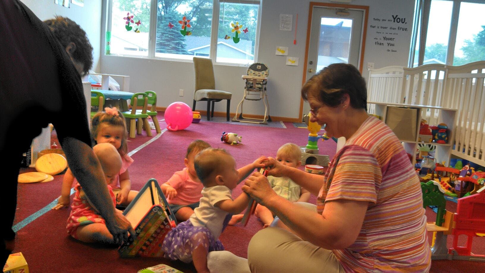 Adults and children playing on a red carpeted floor in a room