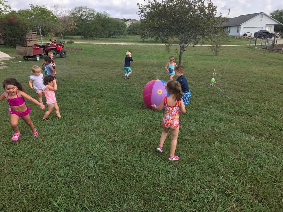 Children playing with a large ball in a grassy area
