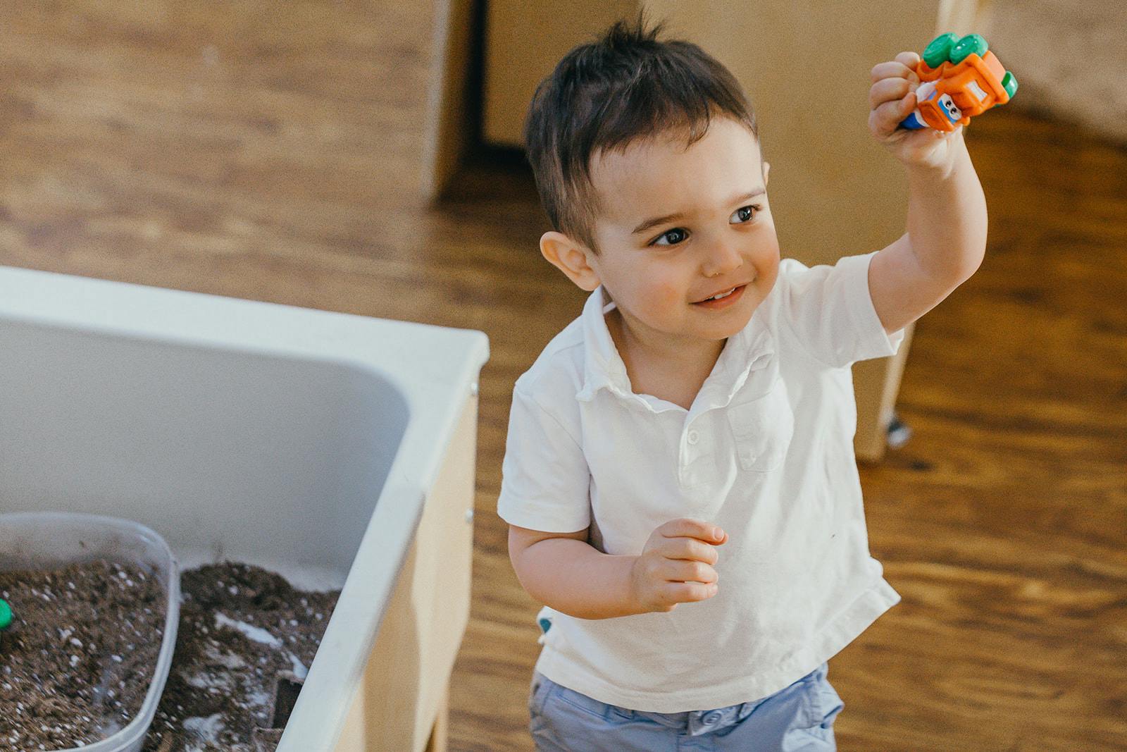 Child holding a toy car in the air