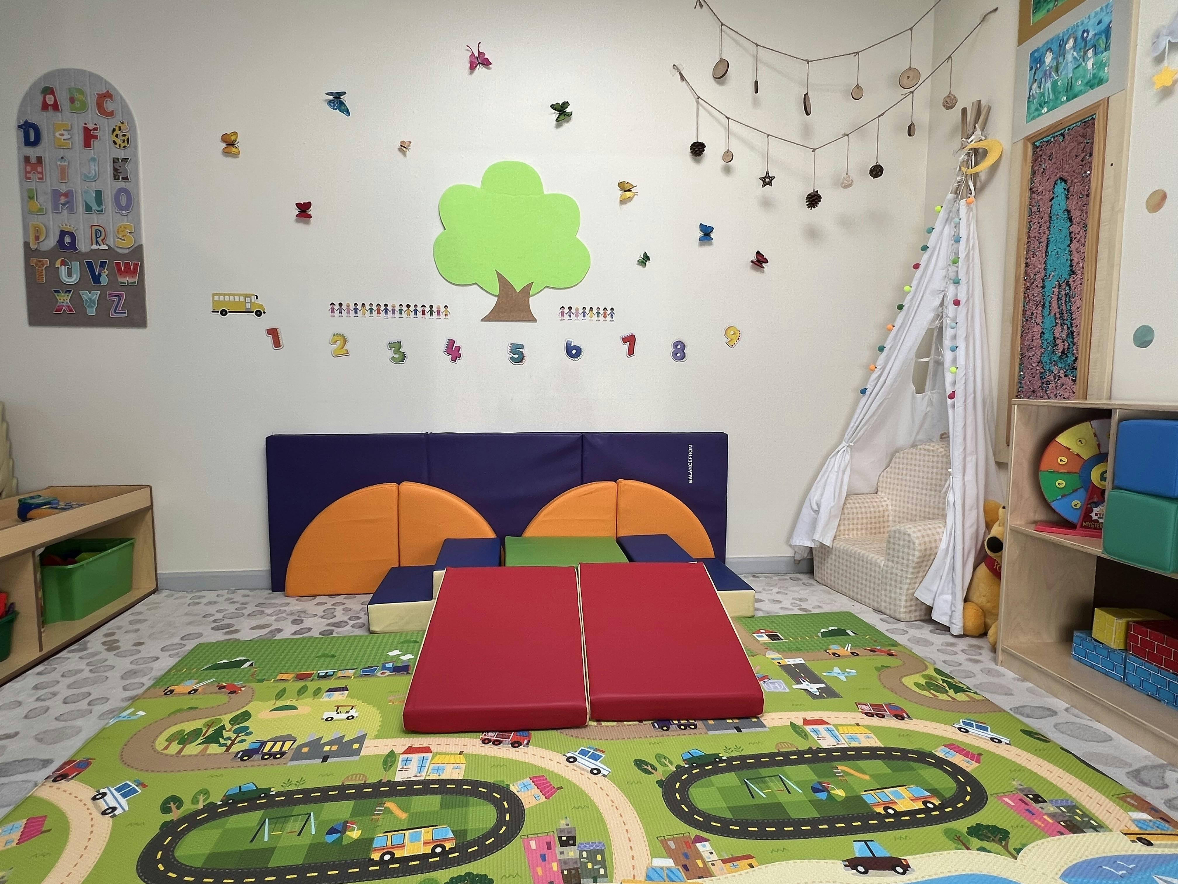 Playroom with soft play equipment, a road rug, and wall decorations