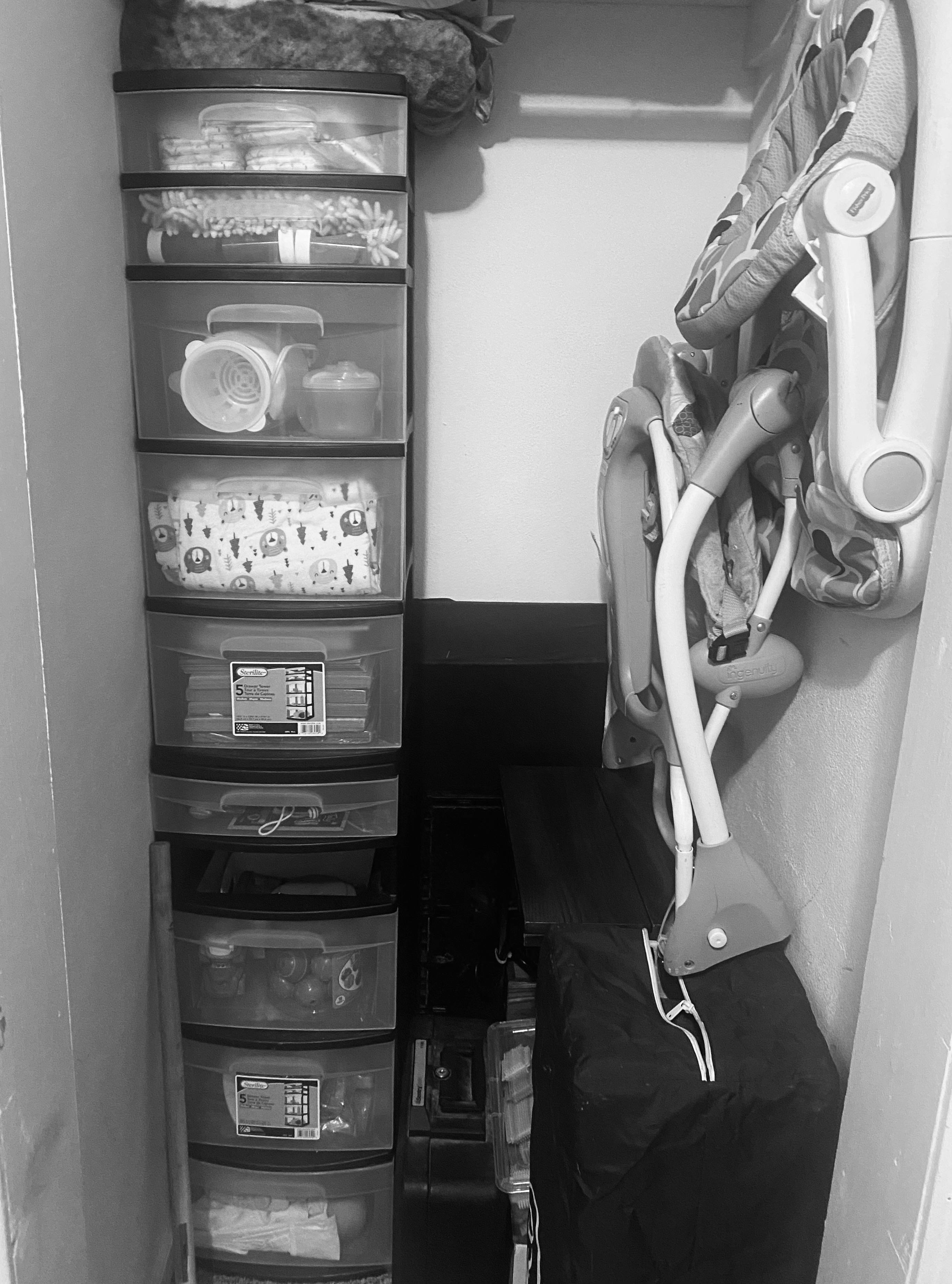 Stack of clear plastic drawers next to a folded baby high chair