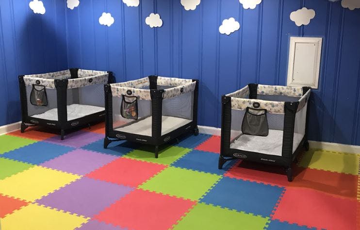 Three playpens in a room with a colorful floor and blue walls