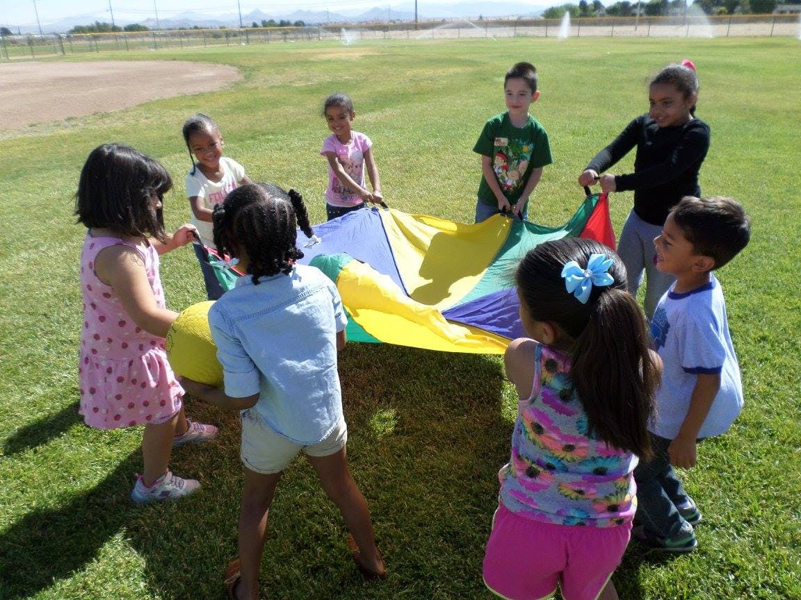 Children playing with a colorful parachute on a grassy field