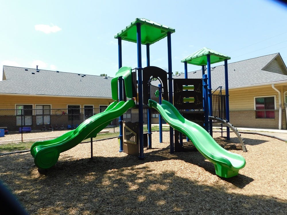 Green and blue playground structure with slides on wood chips