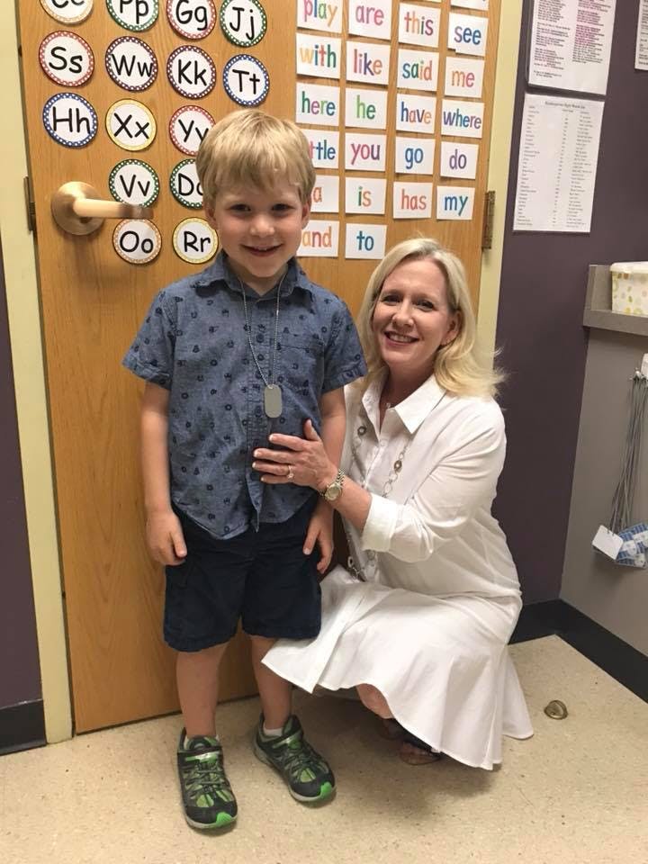 Adult and child standing in front of a door with alphabet and word cards
