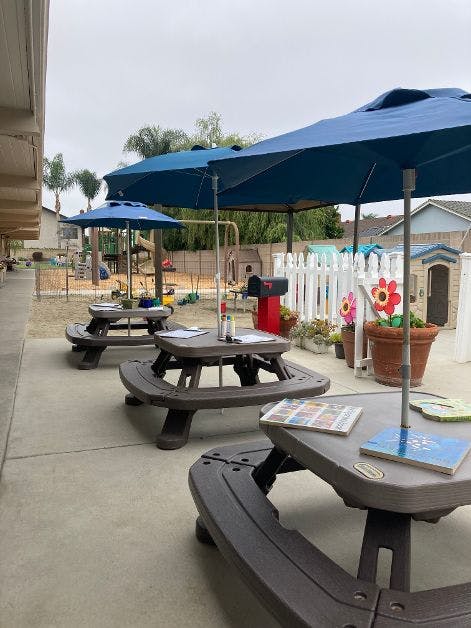 Outdoor picnic tables with blue umbrellas next to a playground