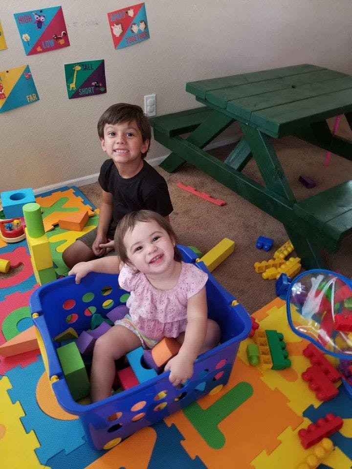Two children playing with blocks on a colorful mat