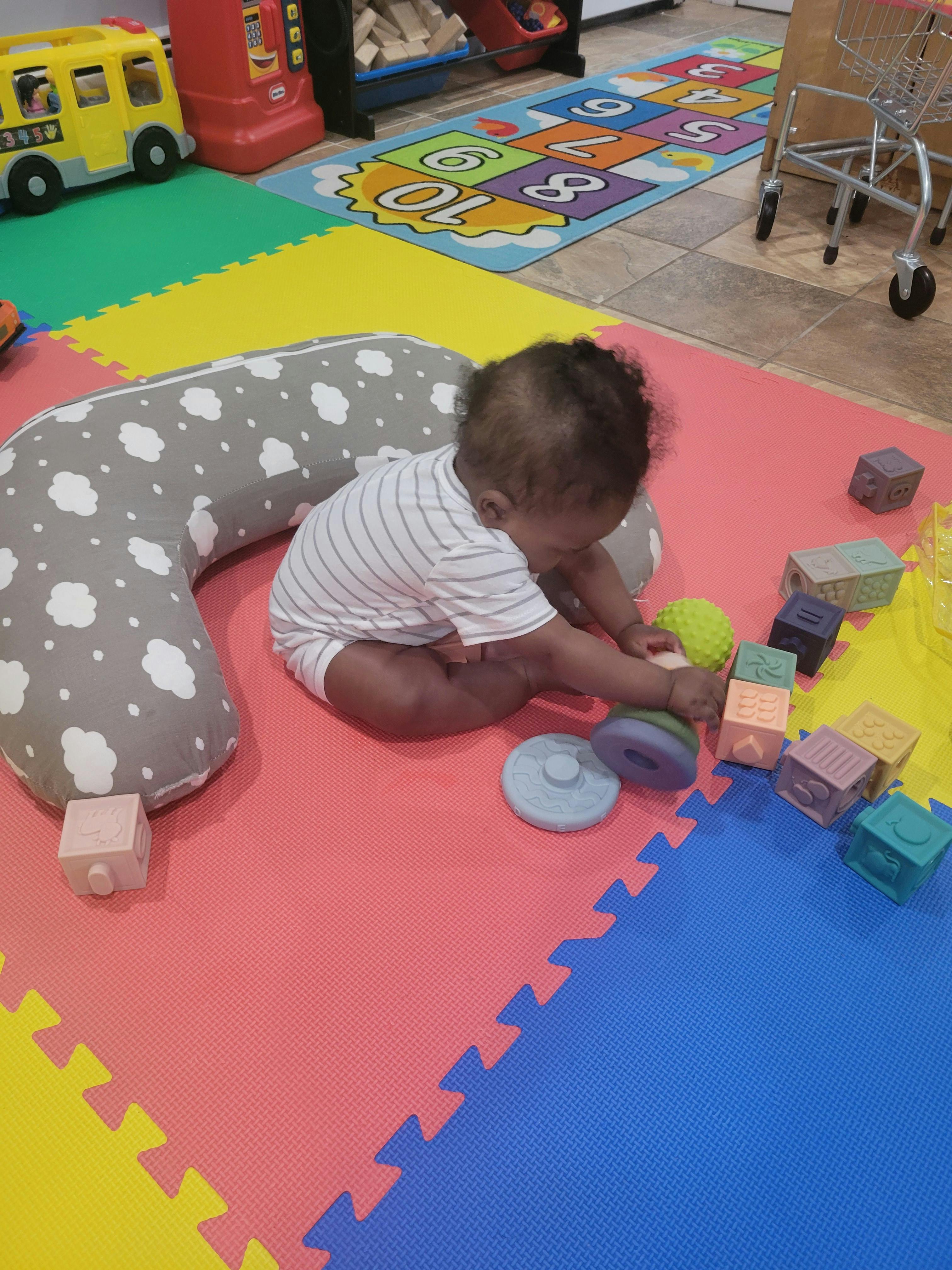 Child playing with blocks and toys on a colorful mat