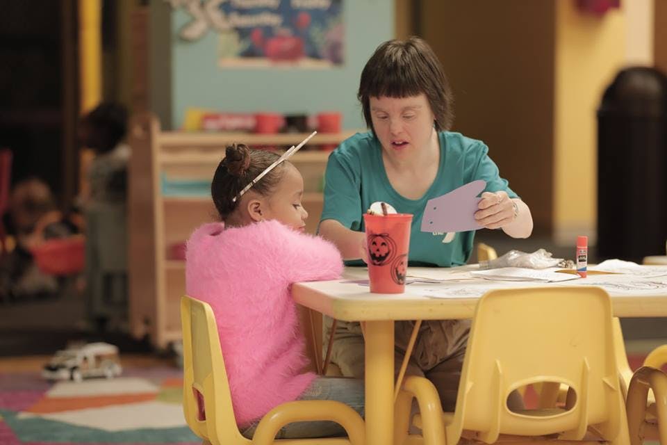 Person and child sitting at a table doing crafts