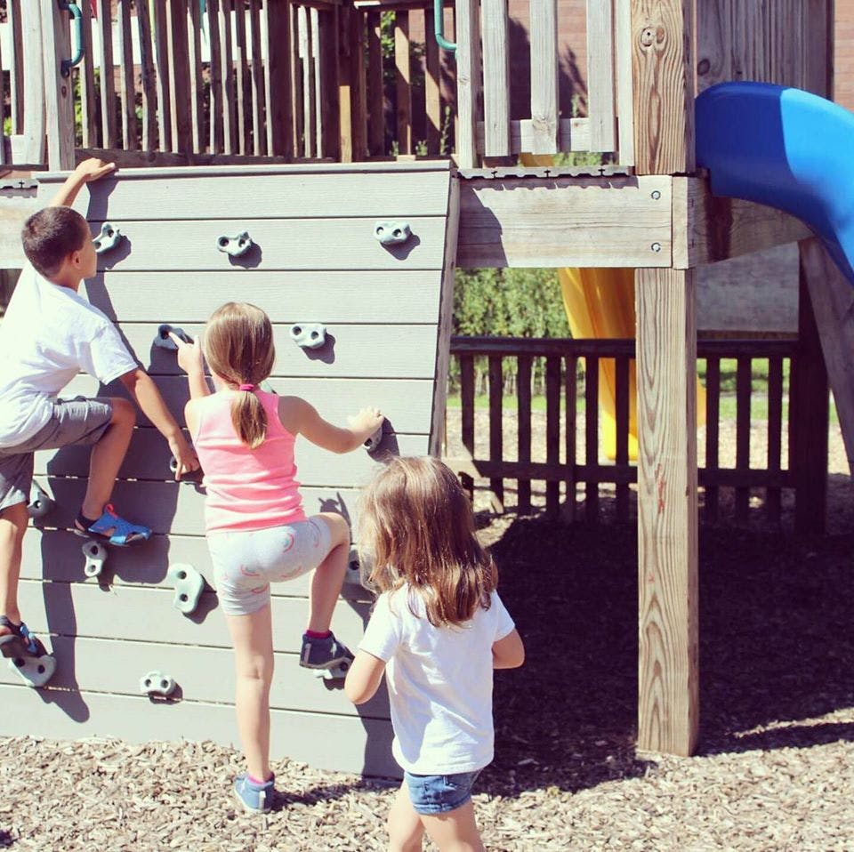 Three children on a climbing wall at a playground