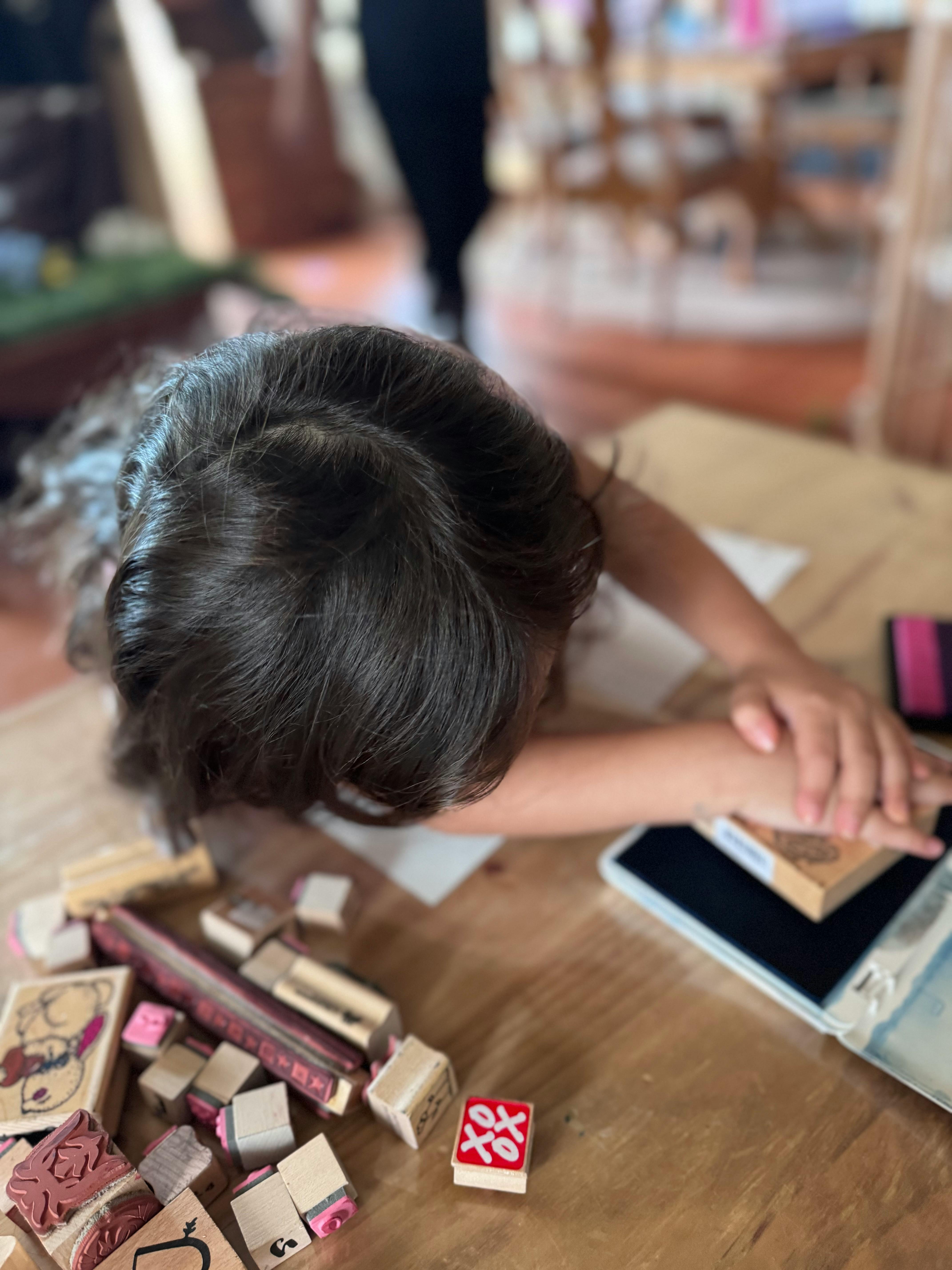 Child stamping on a table with various stamps and ink pads