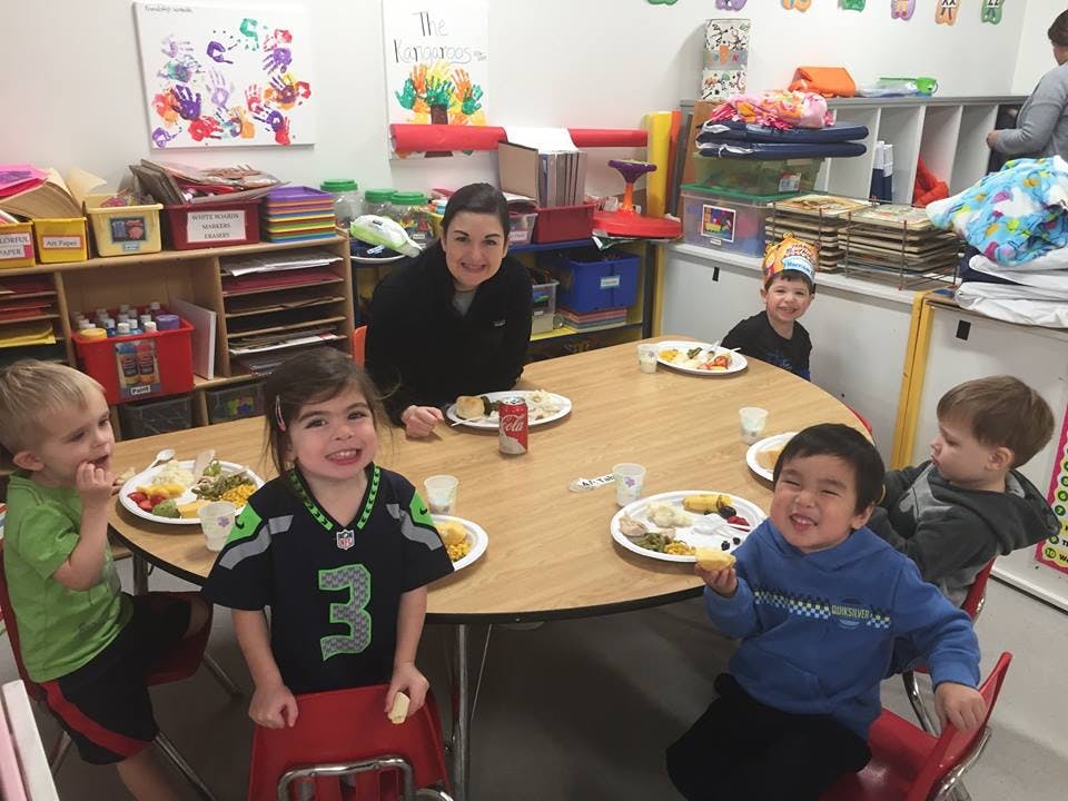 Adult and children sitting around a table with plates of food