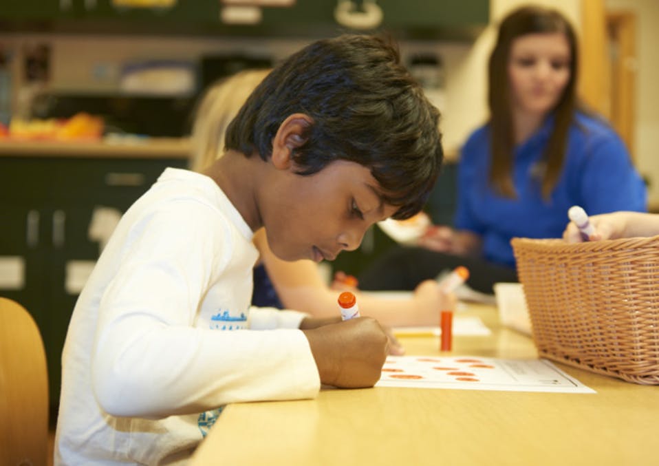 Child writing at a desk in a classroom