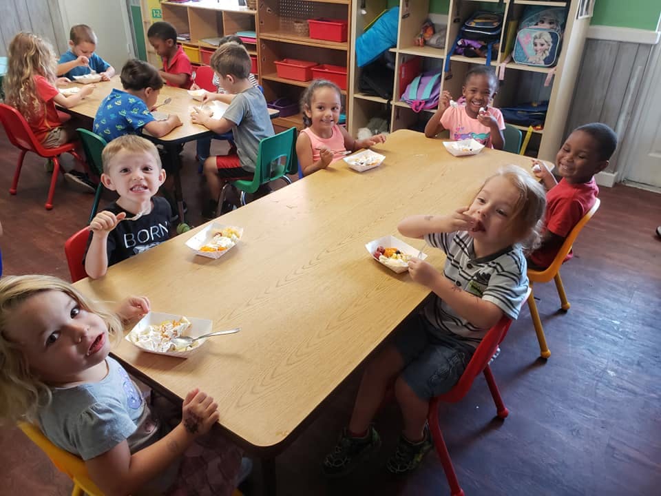 Children eating at tables in a classroom
