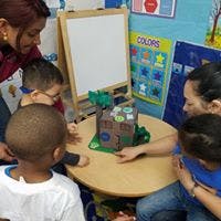Adults and children gathered around a table with a toy