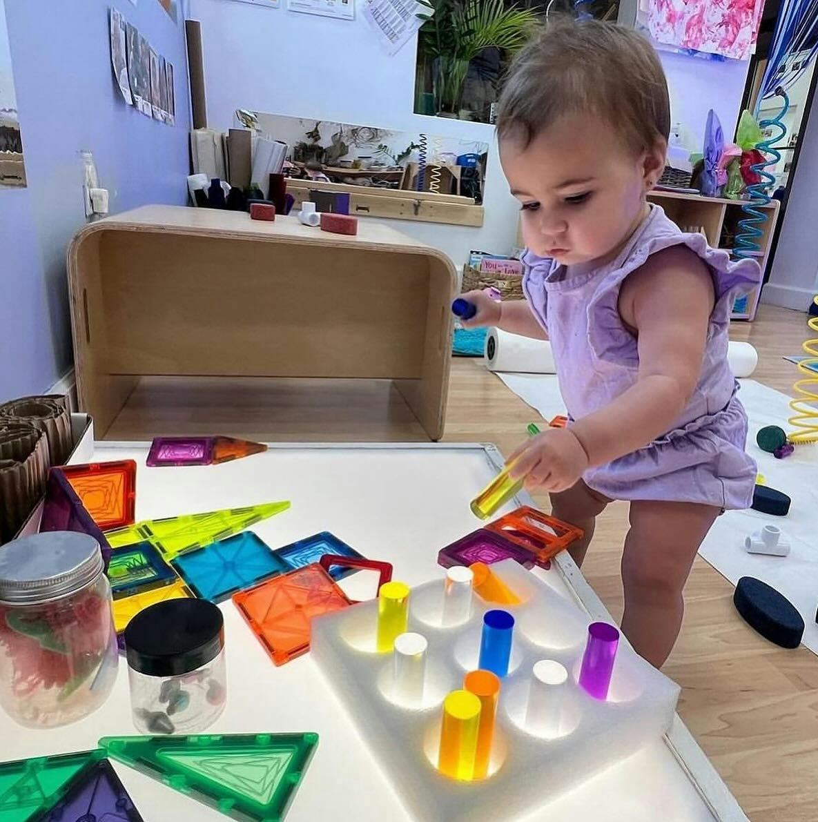 Child playing with colorful blocks and light-up pegs on a table