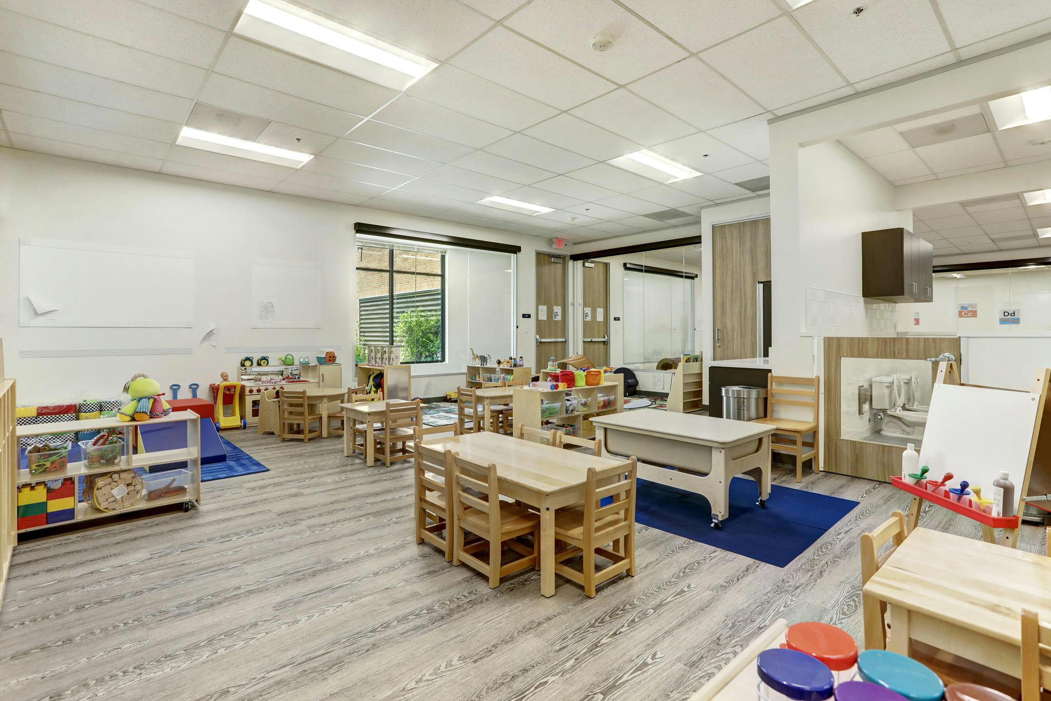 Classroom with child-sized tables and chairs, toys, and activity areas