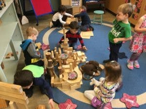 Children playing with wooden blocks in a classroom
