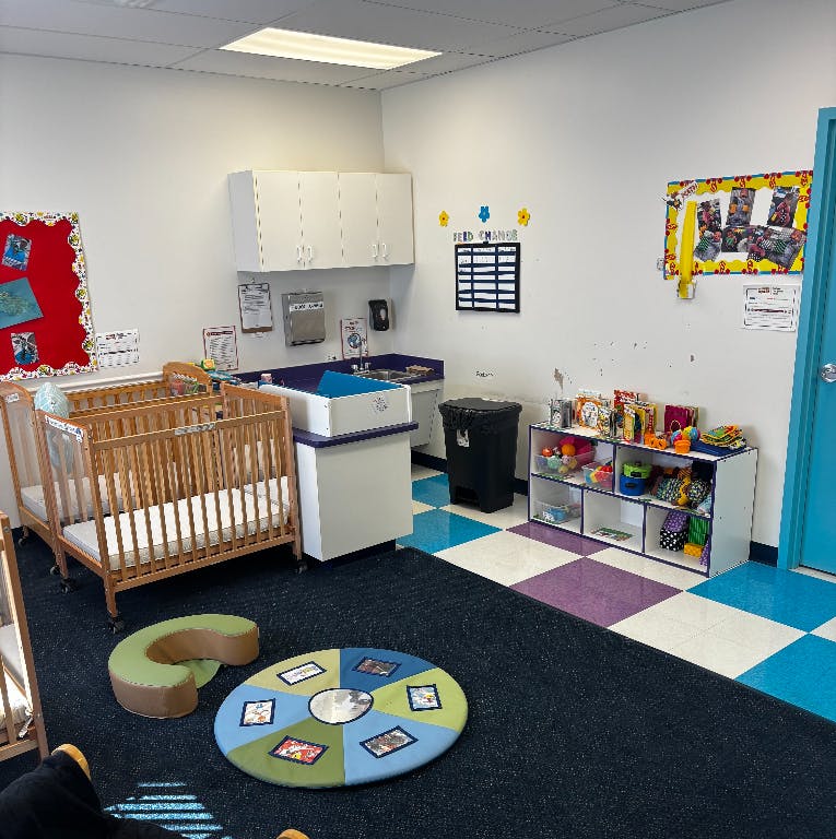 Two cribs and a changing station in a room with a checkered floor
