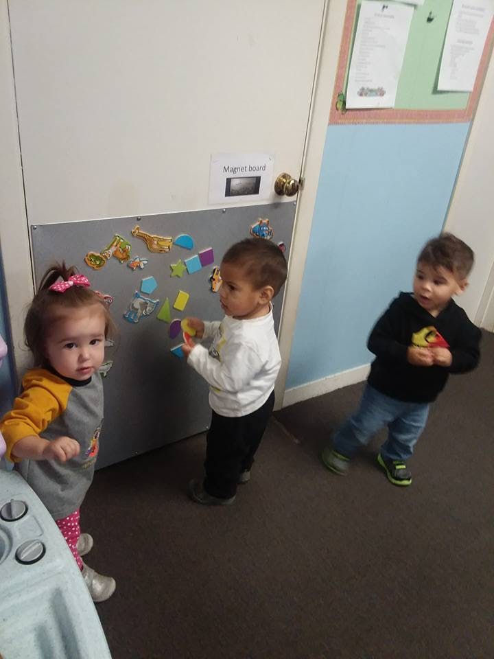 Three children playing with magnets on a door
