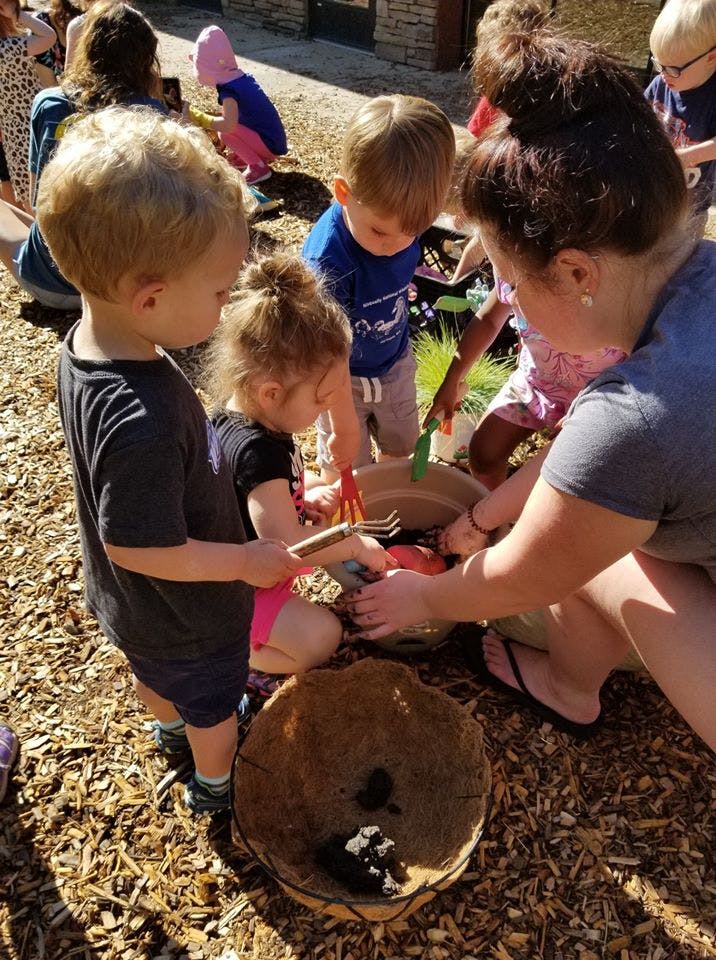 Adult and children playing with bowls and small tools outdoors