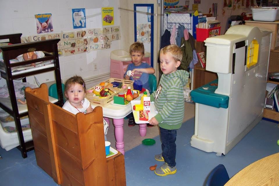 Three children playing in a classroom
