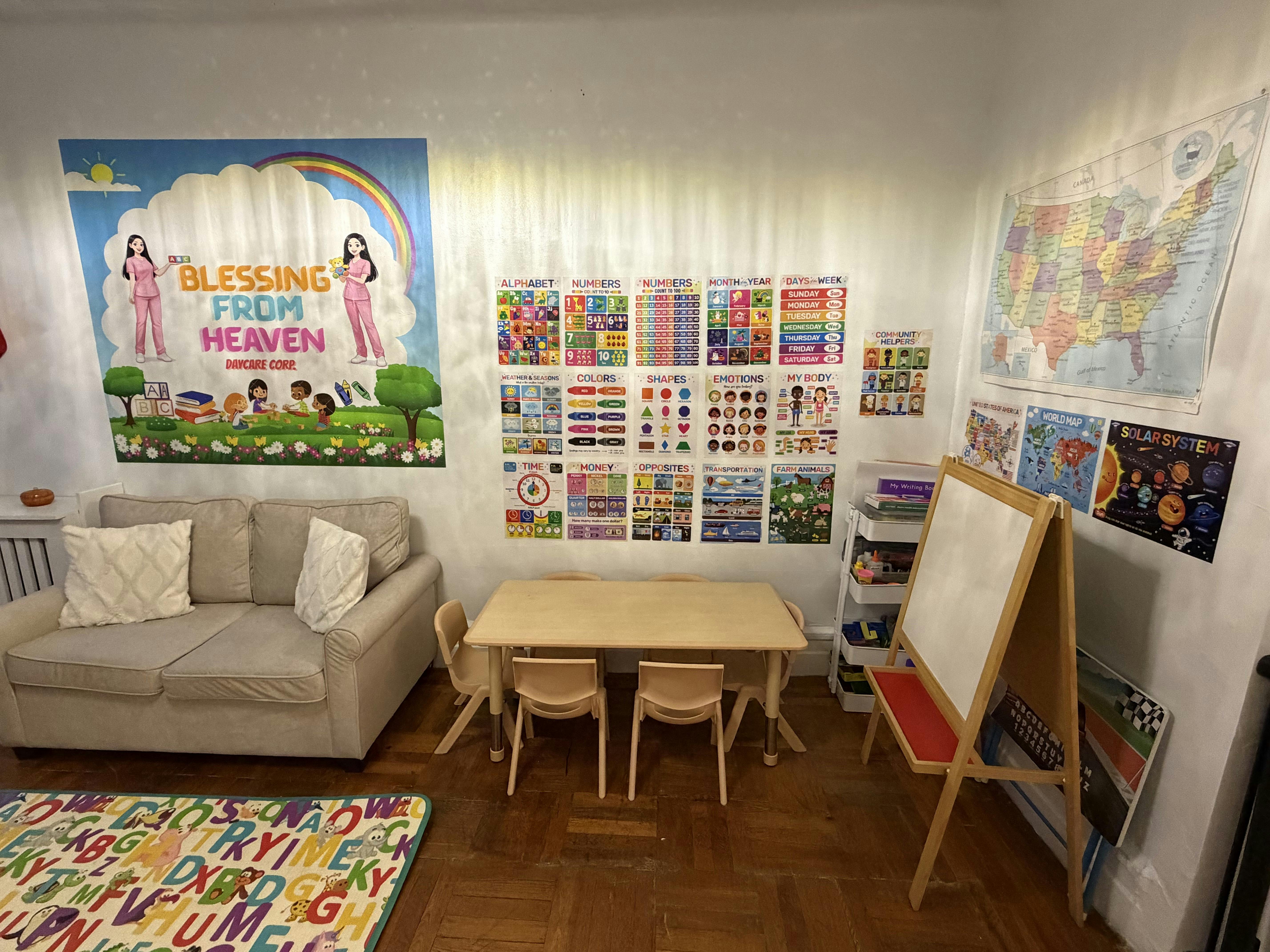 A daycare room with a sofa, child-sized table and chairs, and educational posters