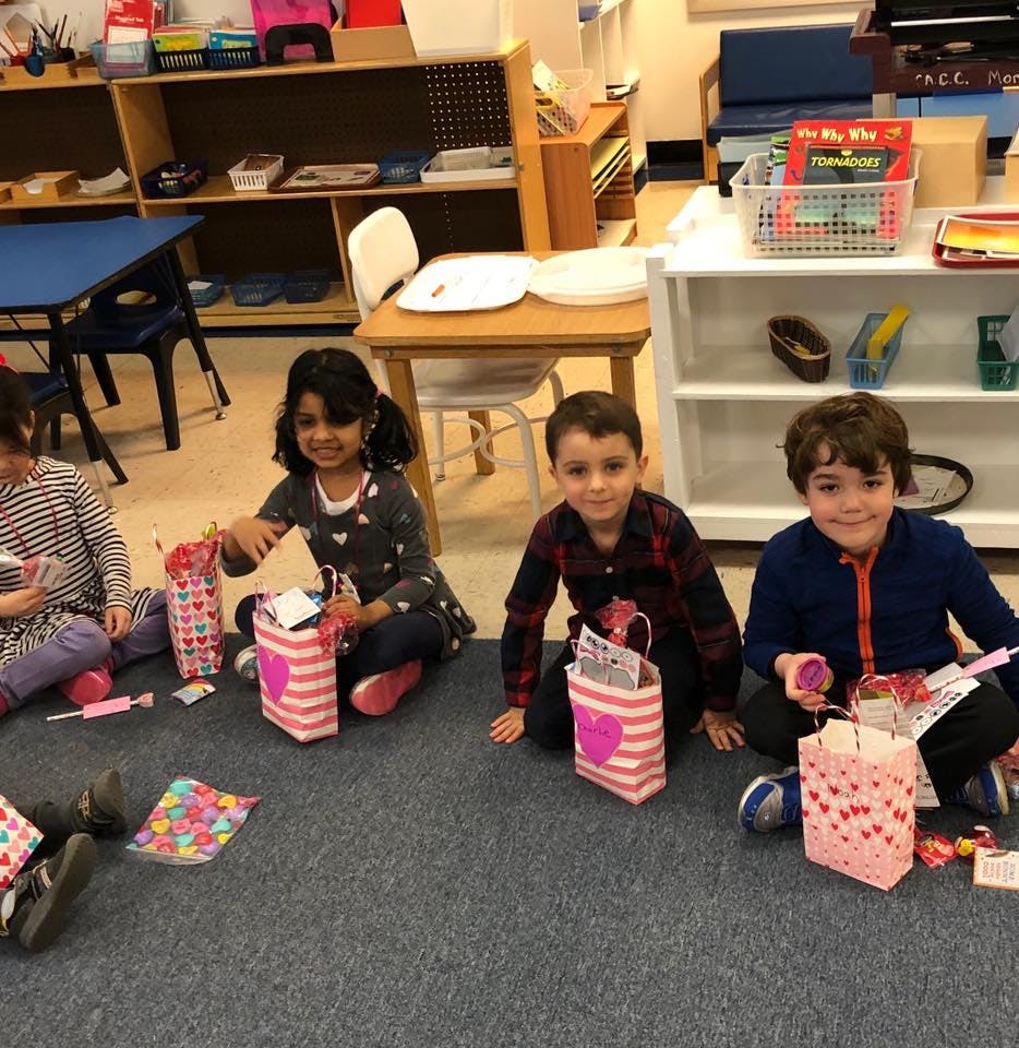 Four children sitting on the floor with small gift bags