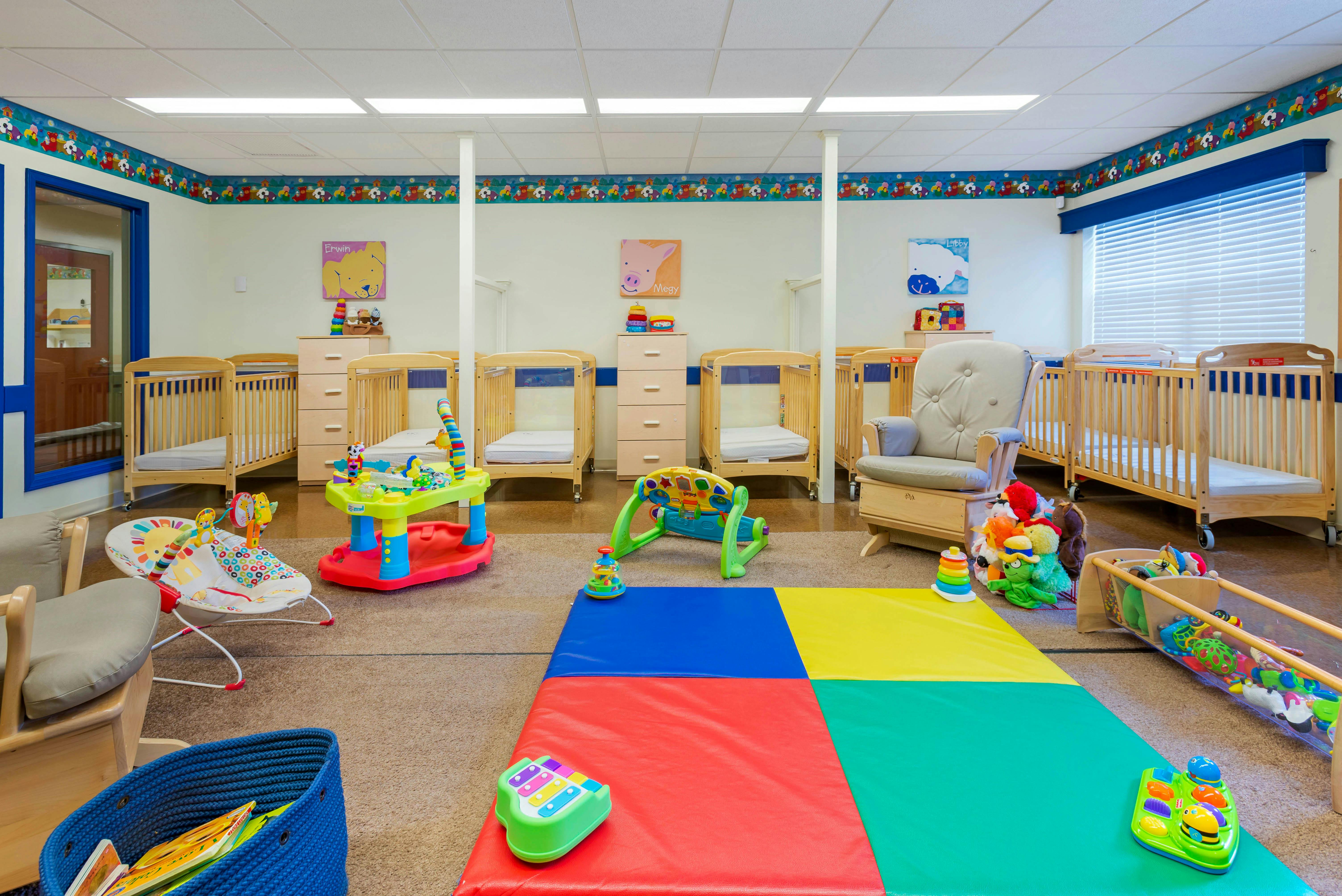 Baby room with cribs, play mats, toys, and a rocking chair