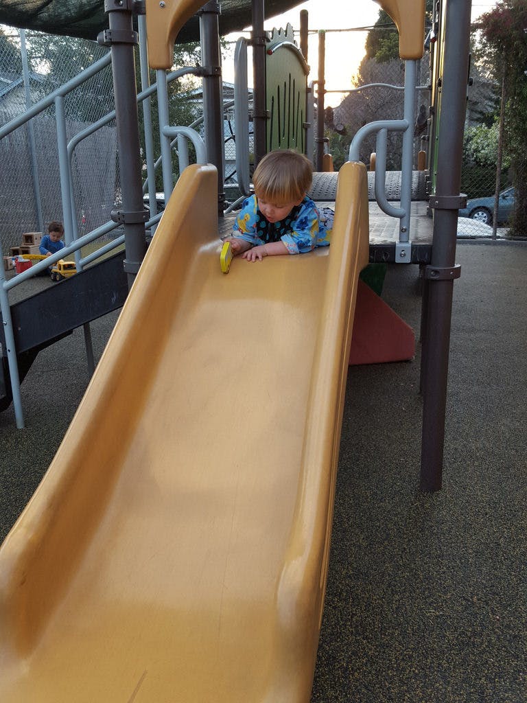 Child on stomach at top of playground slide