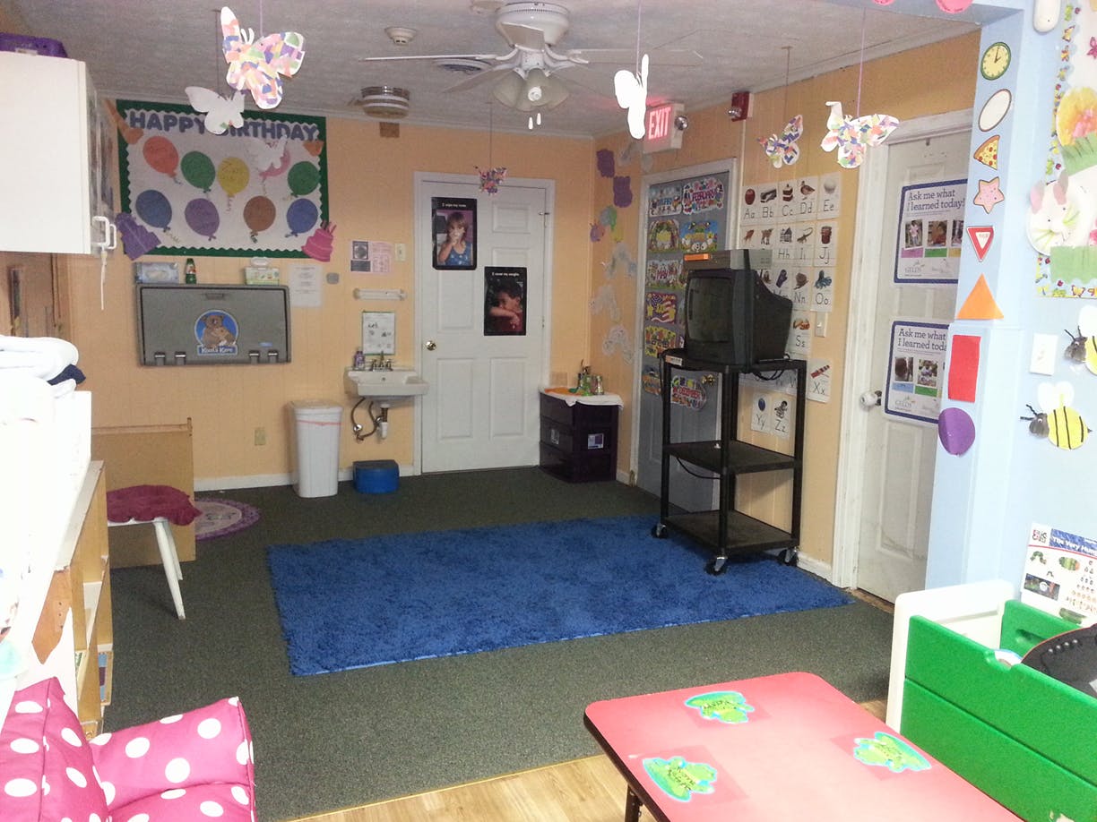 Childcare room with blue rug, small tables, and decorations