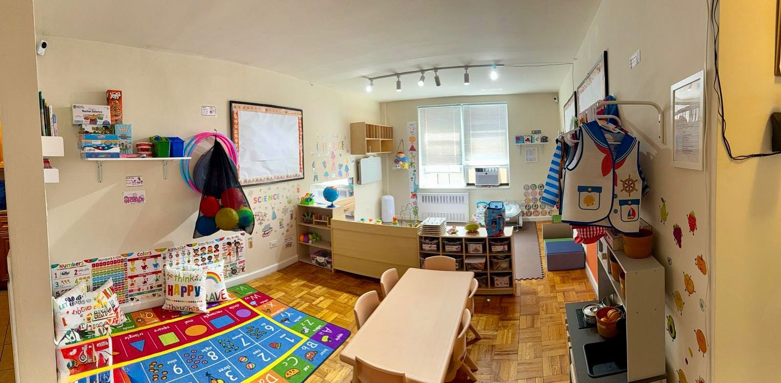 Playroom with colorful rug, small tables, and shelves with toys
