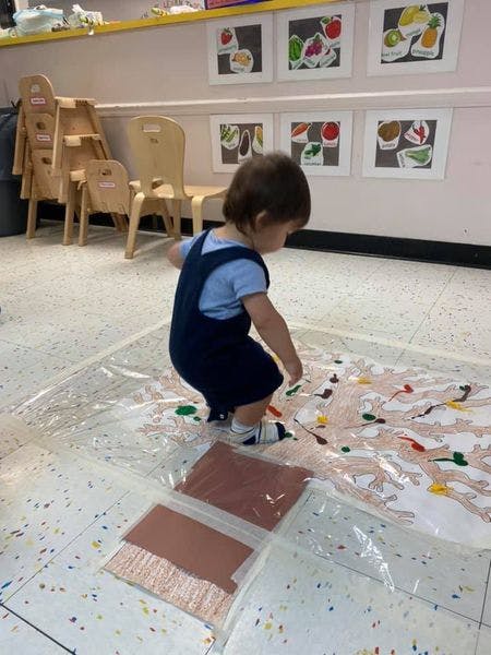 Child playing with paint on a plastic sheet on the floor
