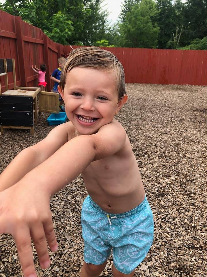 Child in swim trunks reaching out