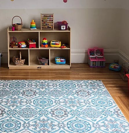 Playroom with a wooden shelf filled with toys and a patterned rug