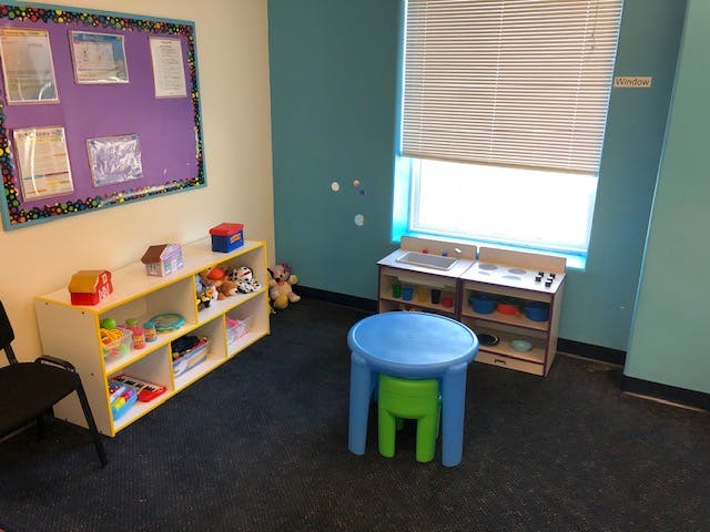 Playroom with a toy shelf, bulletin board, and small table and chairs
