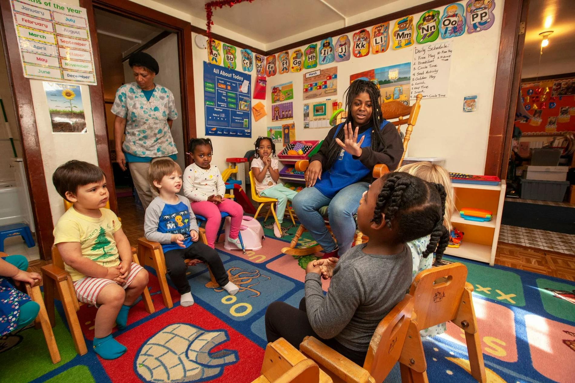 Teacher and group of children sitting in a circle in a daycare classroom