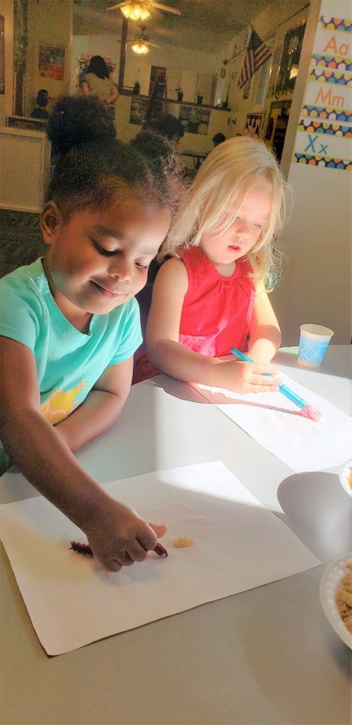 Two children drawing at a table