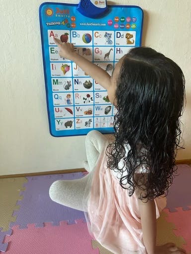 Child pointing at an alphabet chart