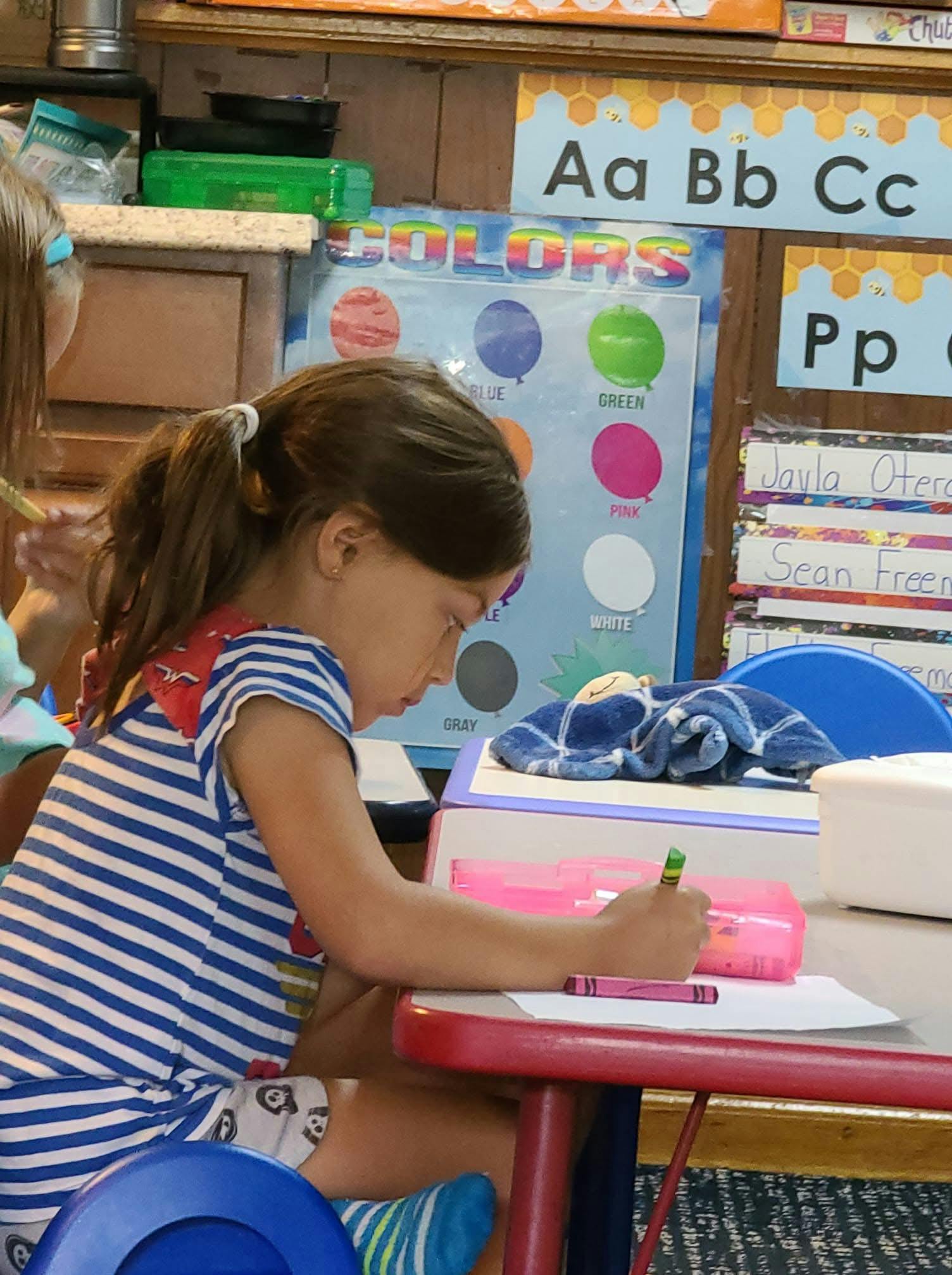 Child coloring at a desk in a classroom