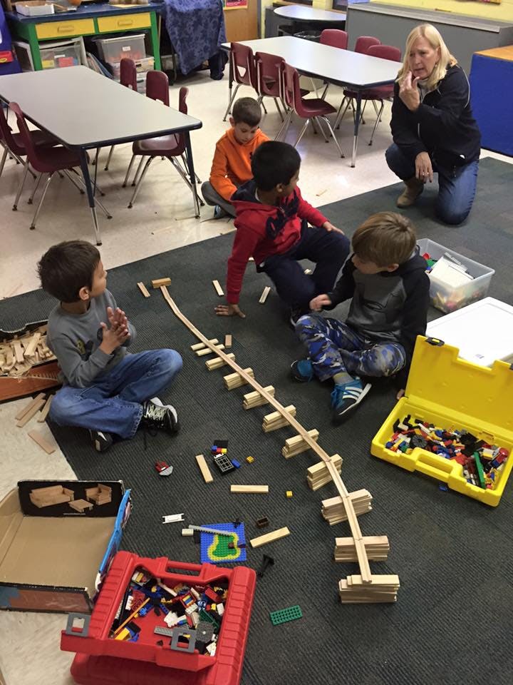 Adult and children on floor building a wooden track