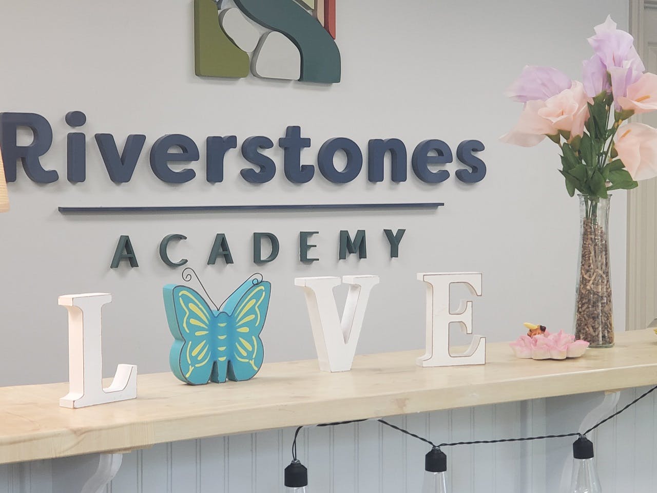 Riverstones Academy sign with decorative letters spelling LOVE on a counter