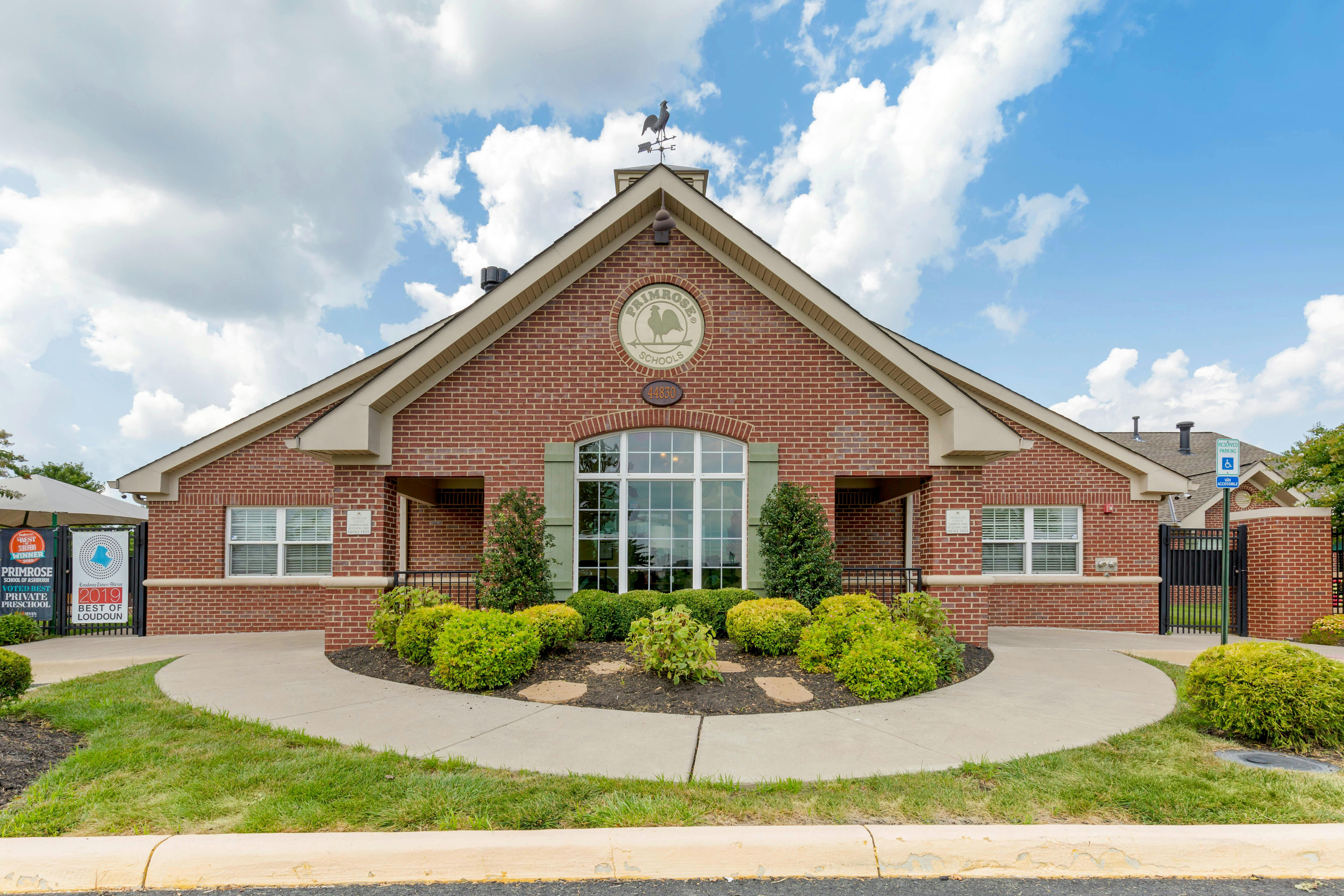 Brick building with a prominent front entrance, large window, and signage for Primrose Schools