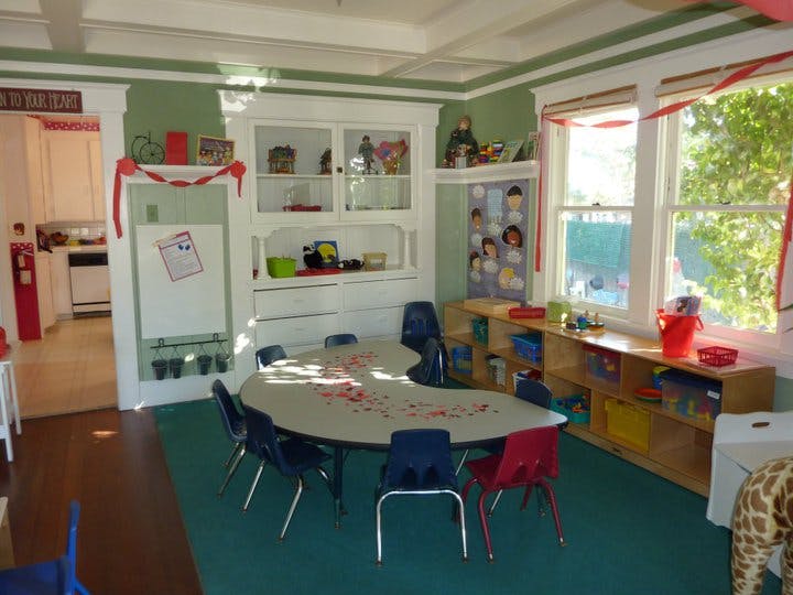 Classroom with a kidney-shaped table and chairs, shelves, and a window