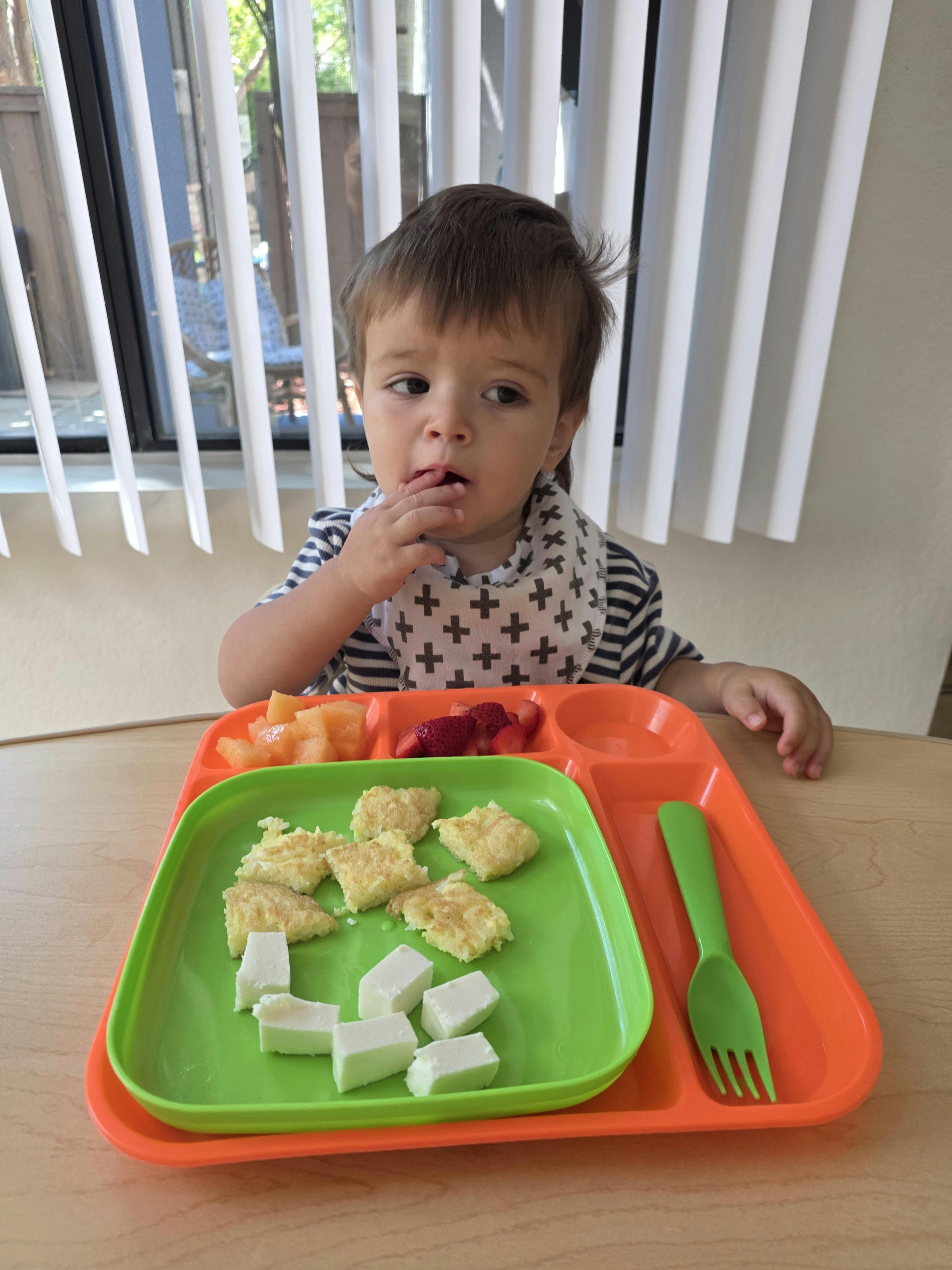 Child sitting at a table with a divided tray of food
