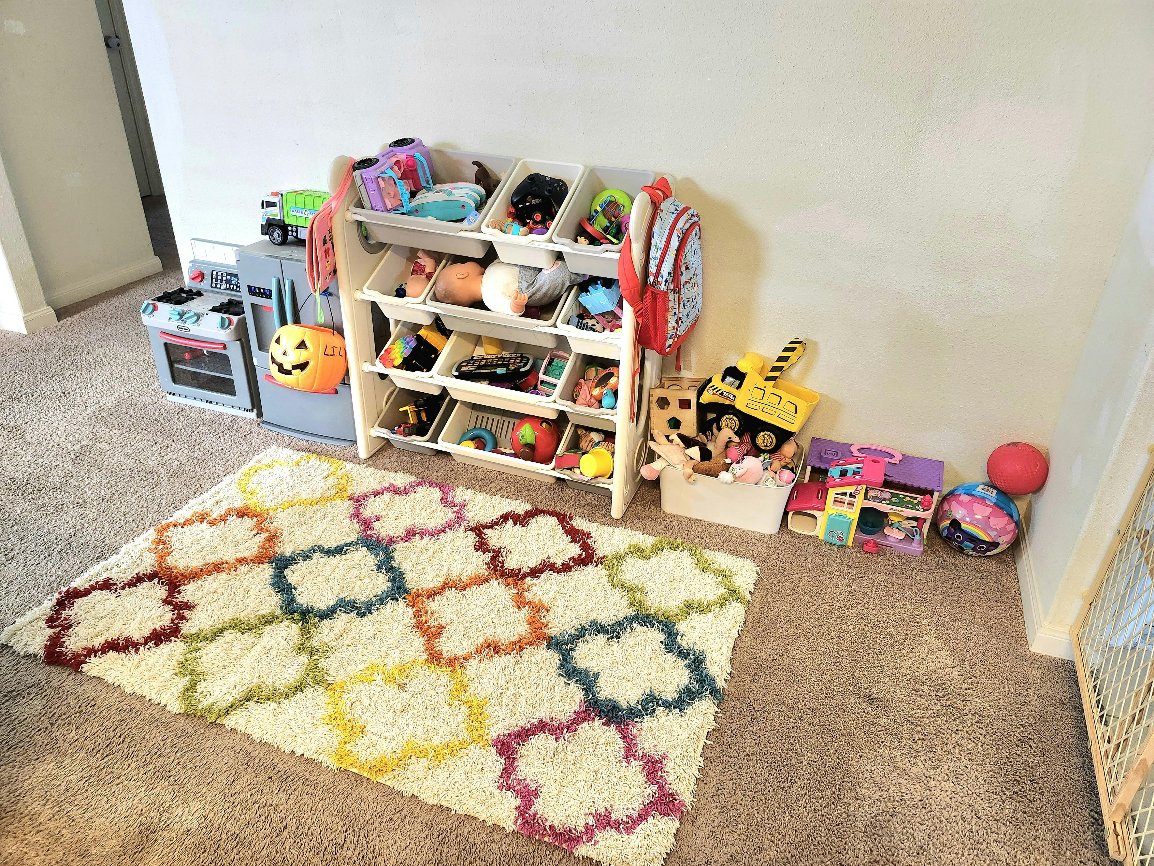 Playroom with a toy organizer, play kitchen, and colorful rug
