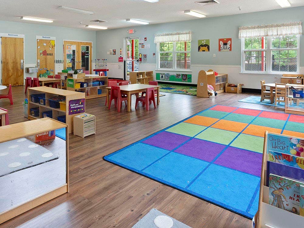 Classroom with small tables, chairs, and play mats