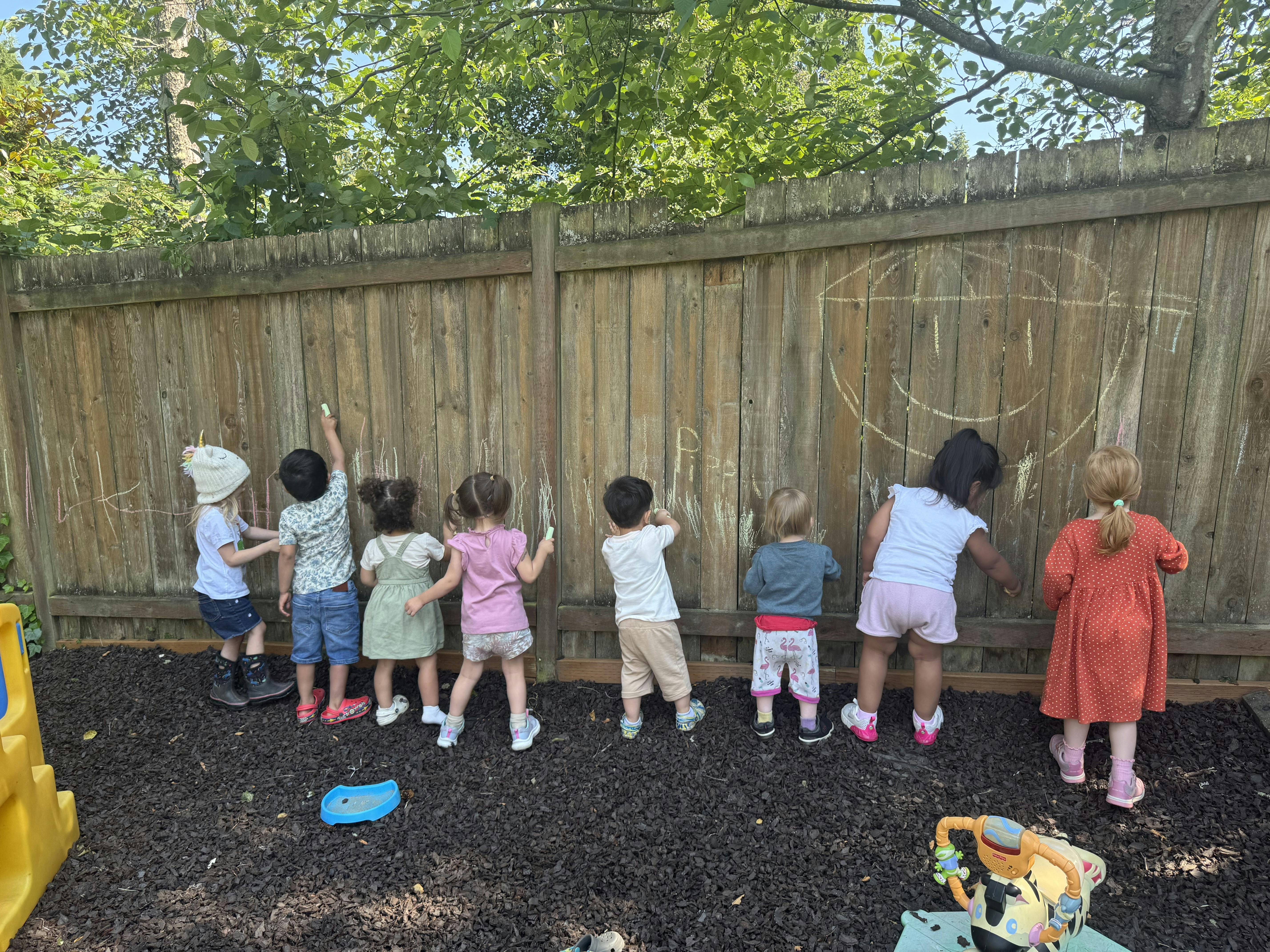 Group of children drawing with chalk on a wooden fence