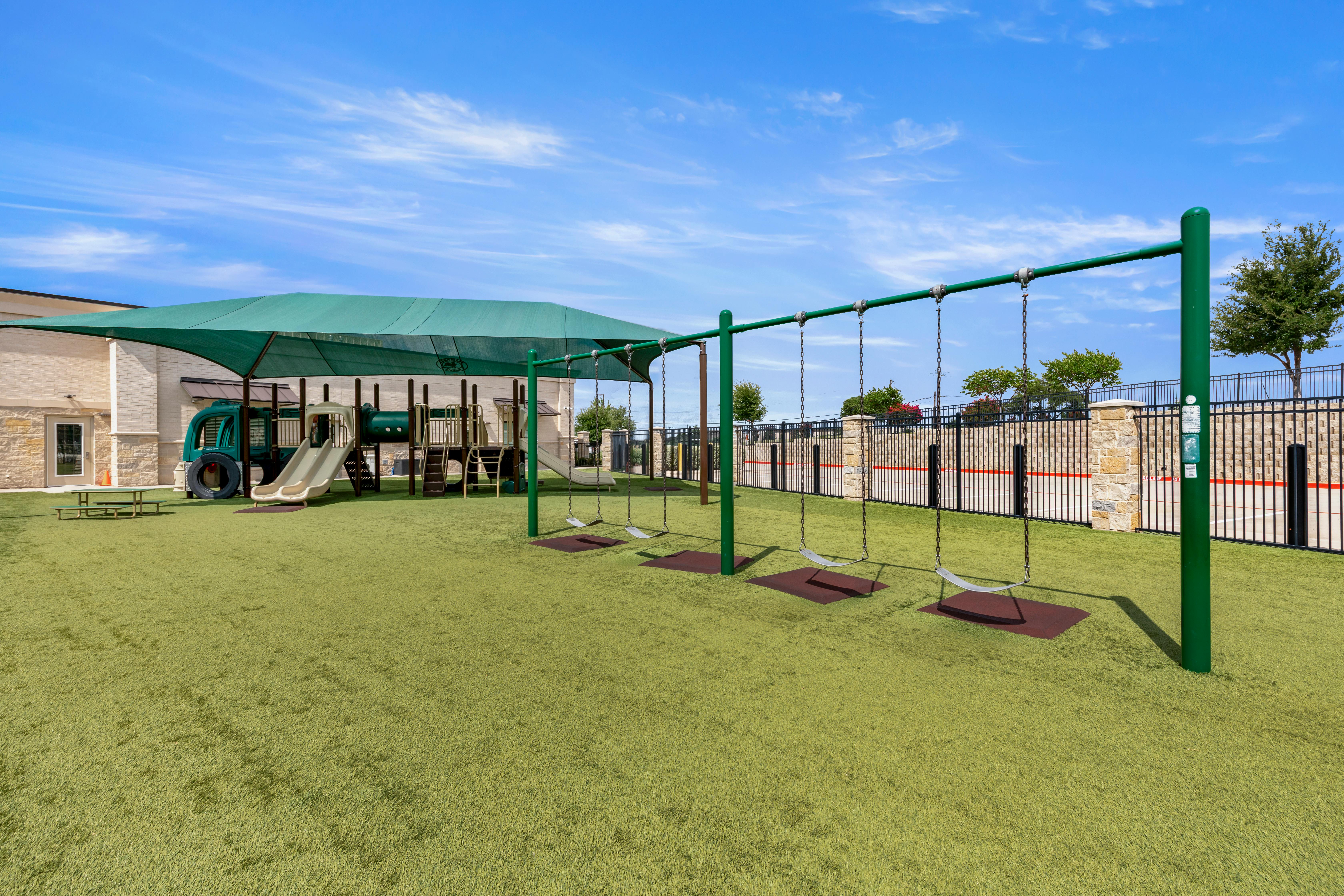 Playground with swings, slides, and climbing structures on artificial turf